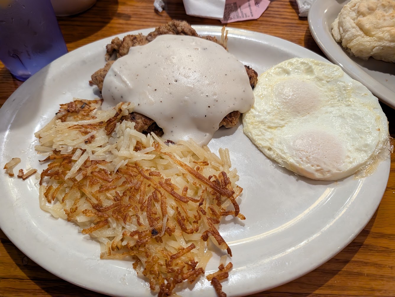 Chicken fried steak smothered in white country gravy, two over-medium eggs, and golden hash browns on a white plate at Old South Restaurant in Russellville, Arkansas.